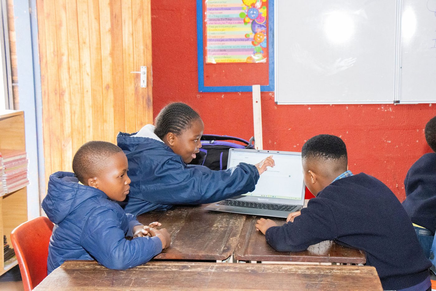 Two learners collaborating on an activity in front of a laptop.